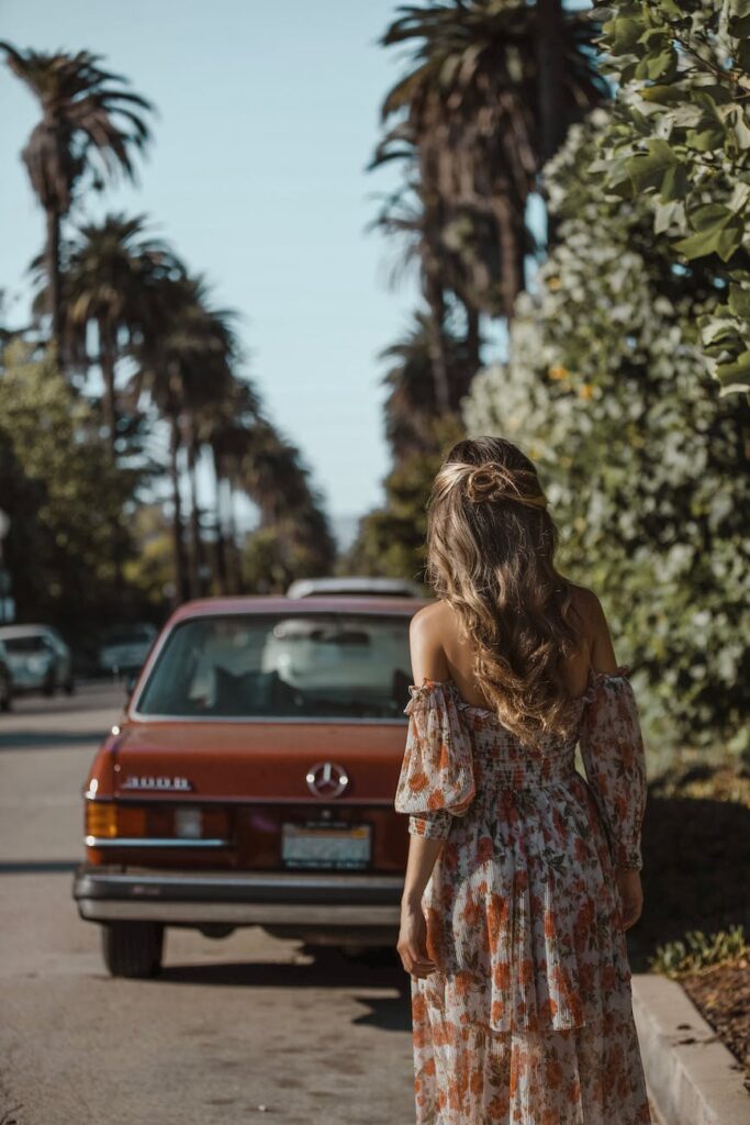 woman standing behind vehicle parked on side of road